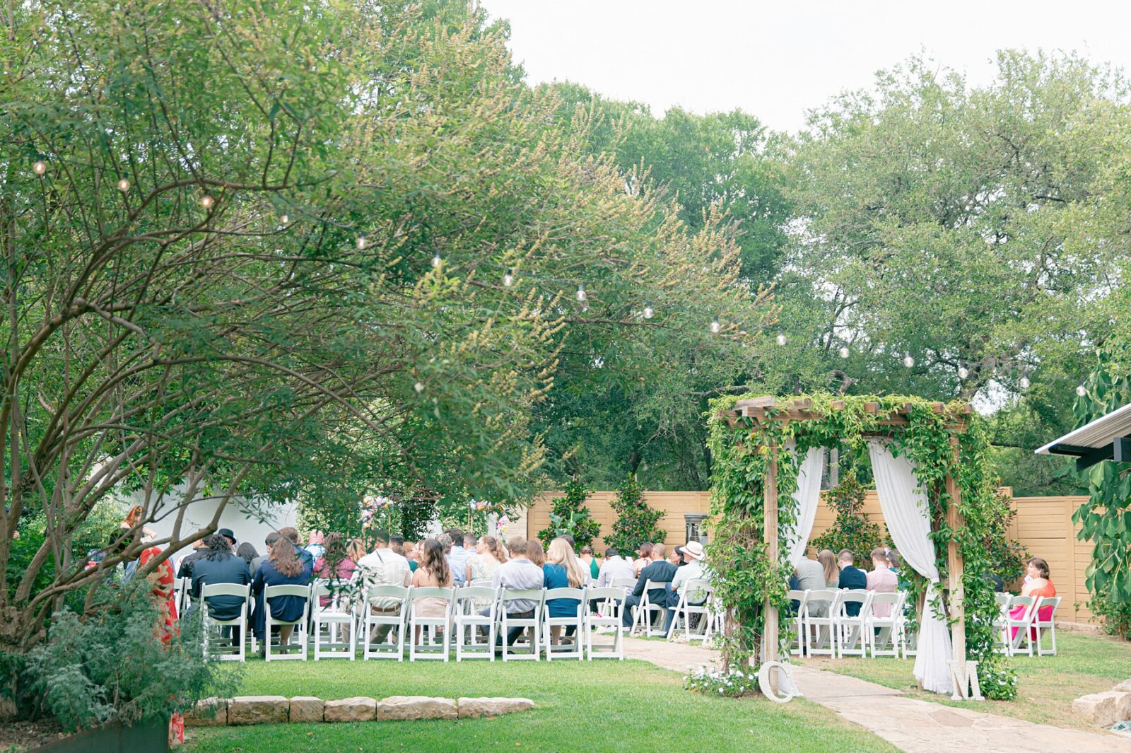 Summer wedding ceremony outside ceremony space at austin garden wedding venue, Austin Wedding at Hummingbird House, with wedding photos by Tara Lyons Photography. Other vendors: Mistique Makeup, Cana Events, Twin Flame Events, Simply Chic Event Rentals, Live Oak Photo Booth