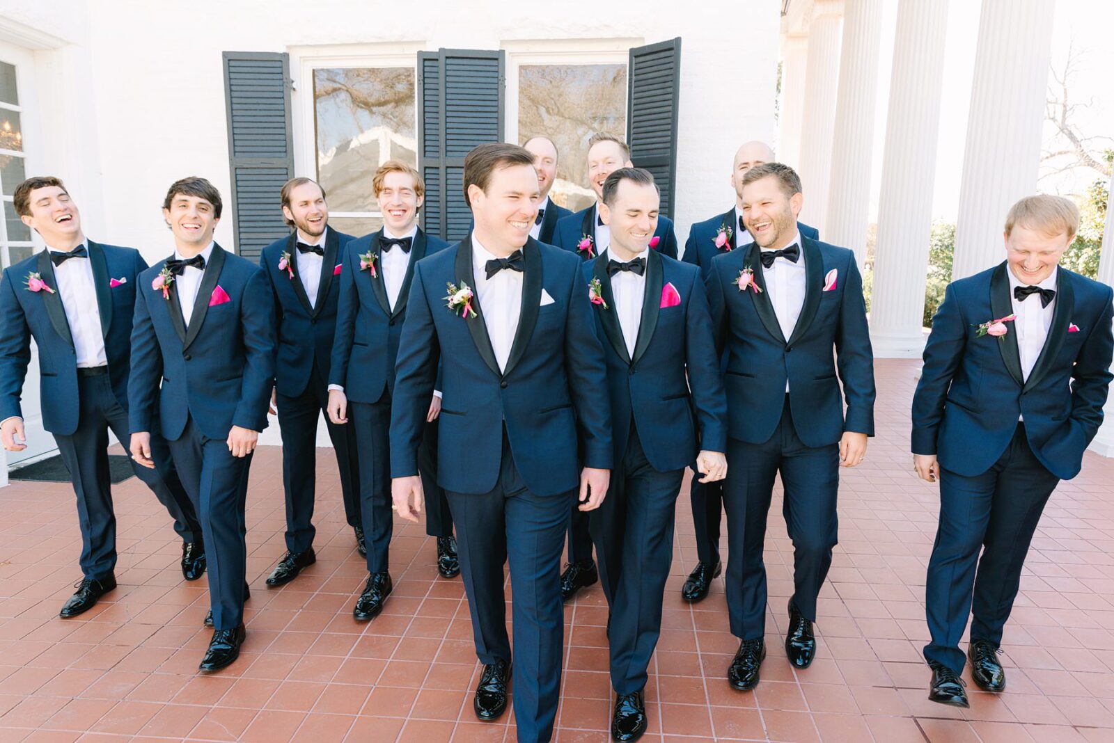 groom and groomsmen, large wedding party, twelve groomsmen, pink pocket squares for wedding, pink wedding details for groom, navy and black wedding suits, at Woodbine mansion in round rock texas, wedding photos by Tara Lyons Photography, planning by The event shop